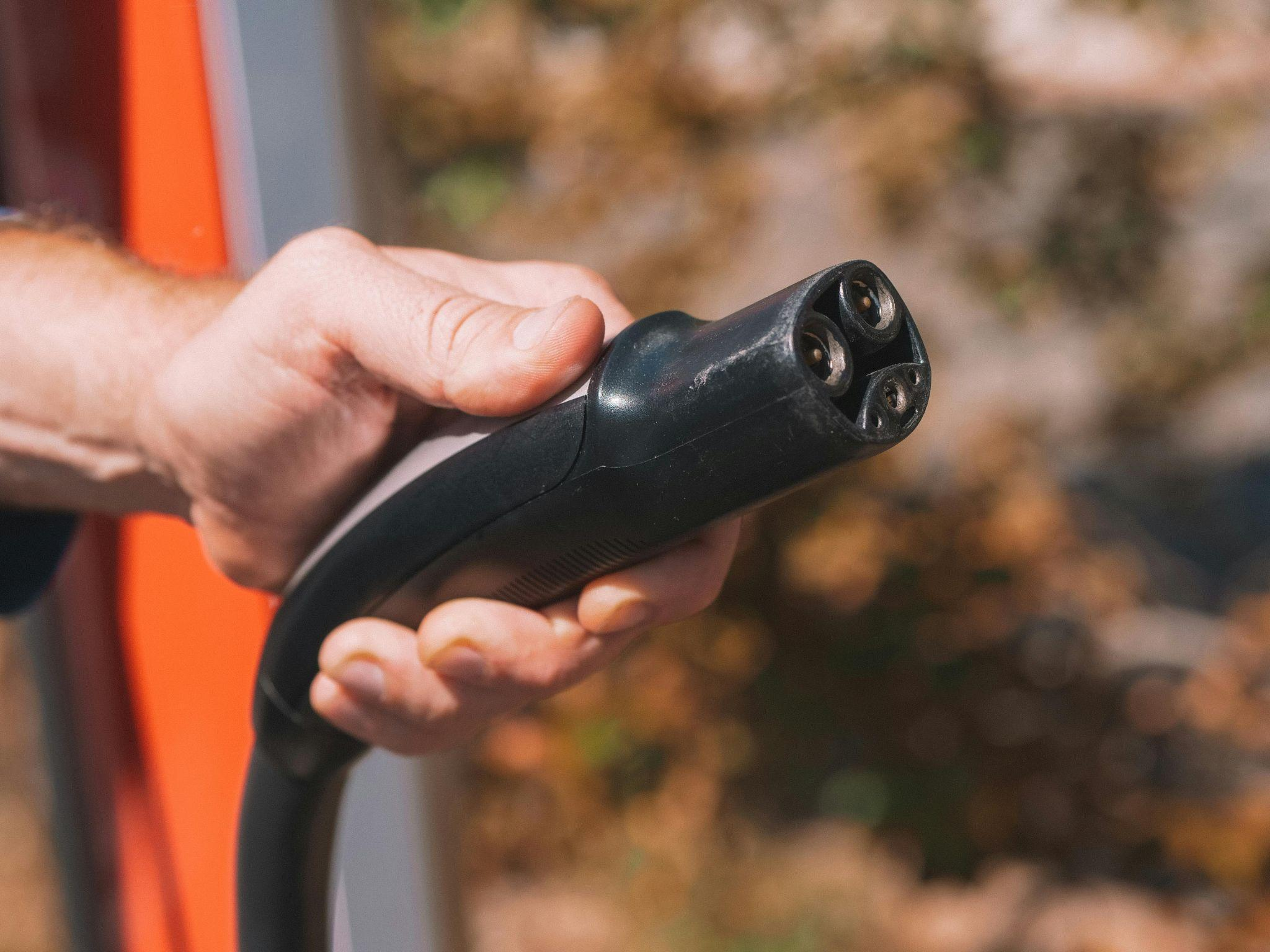 person holding an electric vehicle charging connector