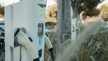 outdoor electric vehicle charging station with plugged-in cable
