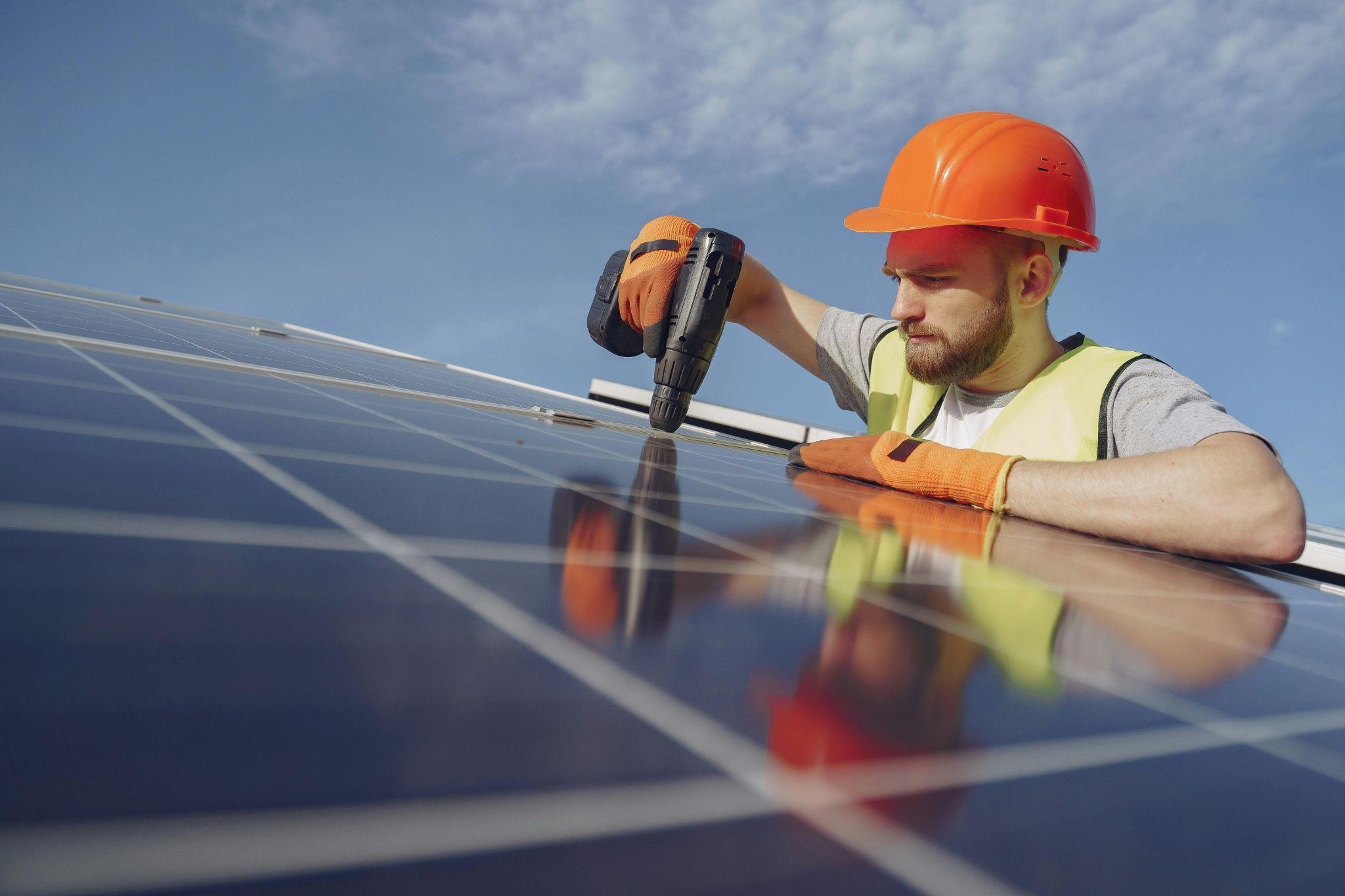 Solar technician securing a solar panel using power tools