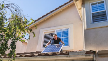 Technician removing an old solar panel from a residential rooftop for replacement.