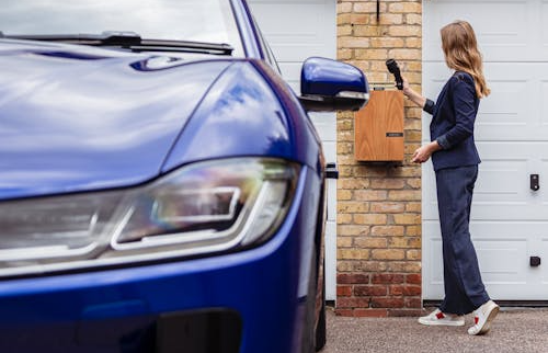 Woman connecting a universal EV charger to her electric vehicle at home.
