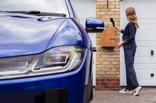 Woman connecting a universal EV charger to her electric vehicle at home.