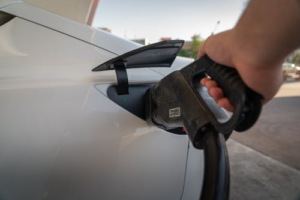 Close-up of a hand plugging a Tesla charger into an electric vehicle