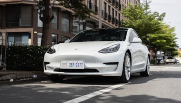 A high-end electric sedan driving along a road.