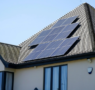 A home with a set of solar panels installed across the primary roof section.