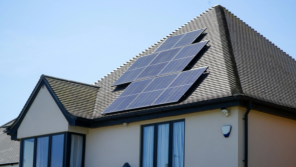 A home with a set of solar panels installed across the primary roof section.