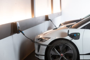 A white electric car connected to a wall-mounted charger.