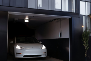  A modern garage showing a Tesla and an EV charger installed on the adjacent wall. 