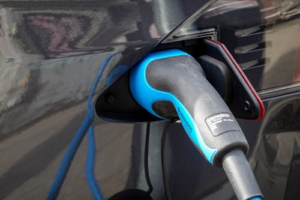 A close-up shot of an electric car’s charging port with the cable plugged in