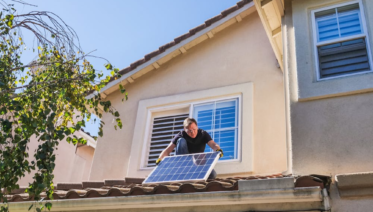 a solar technician on a residential roof inspecting panels
