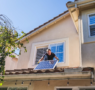 a solar technician on a residential roof inspecting panels