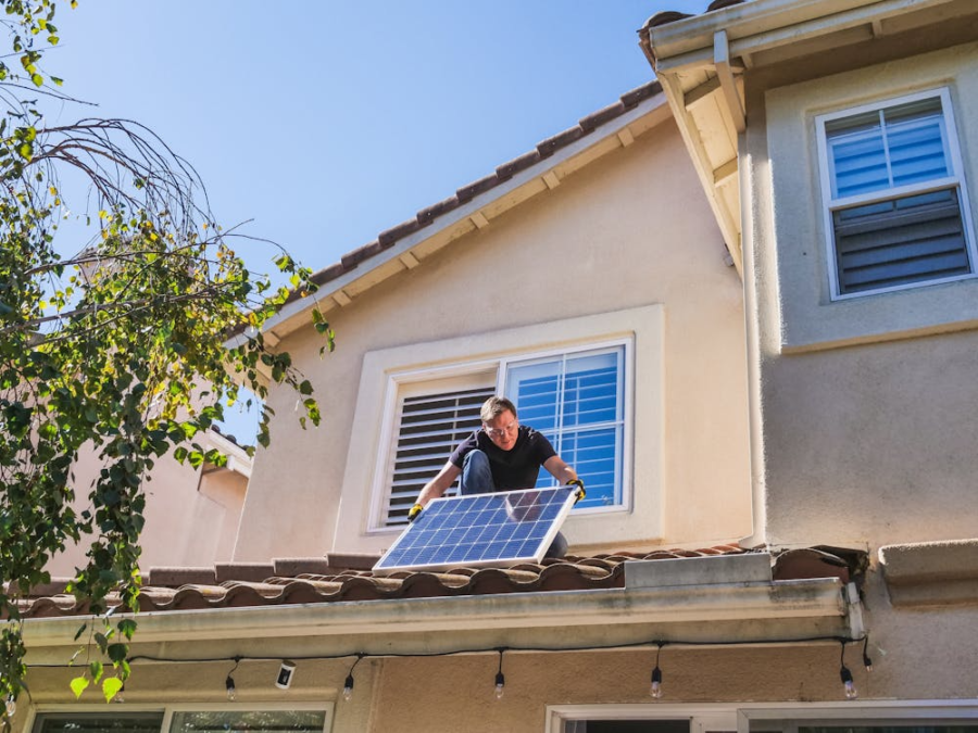 a solar technician on a residential roof inspecting panels