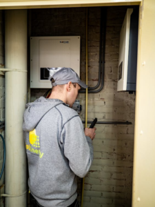 a solar technician inspecting racking hardware and conduit on a residential rooftop solar system