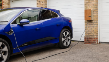a car plugged into a Level 2 home EV charger in a clean residential garage in the Bay Area