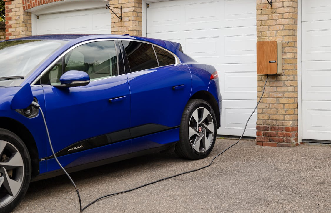 a car plugged into a Level 2 home EV charger in a clean residential garage in the Bay Area