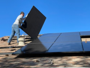 Worker installing solar panels on a rooftop under sunny weather conditions