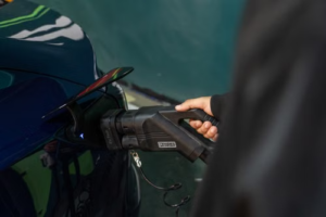 Hand inserting an EV charging connector into an electric vehicle before charging.