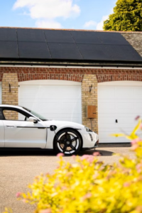 Residential home with rooftop solar panels and an electric vehicle charging in the driveway.