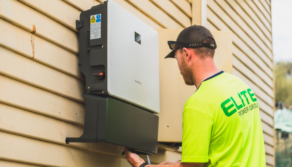 Skilled technician installing a residential solar inverter system outdoors.