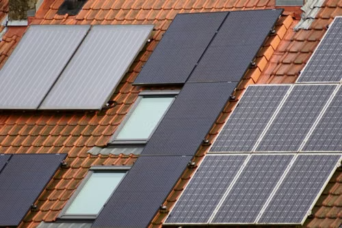 Close-up view of solar panels mounted on a tiled residential roof under clear daylight conditions.