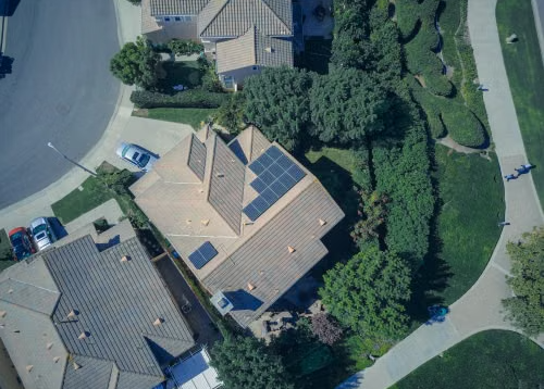 Top-down aerial view of a residential home with solar panels installed on the roof.