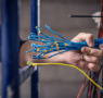 Technician inspecting wiring beneath residential solar panels